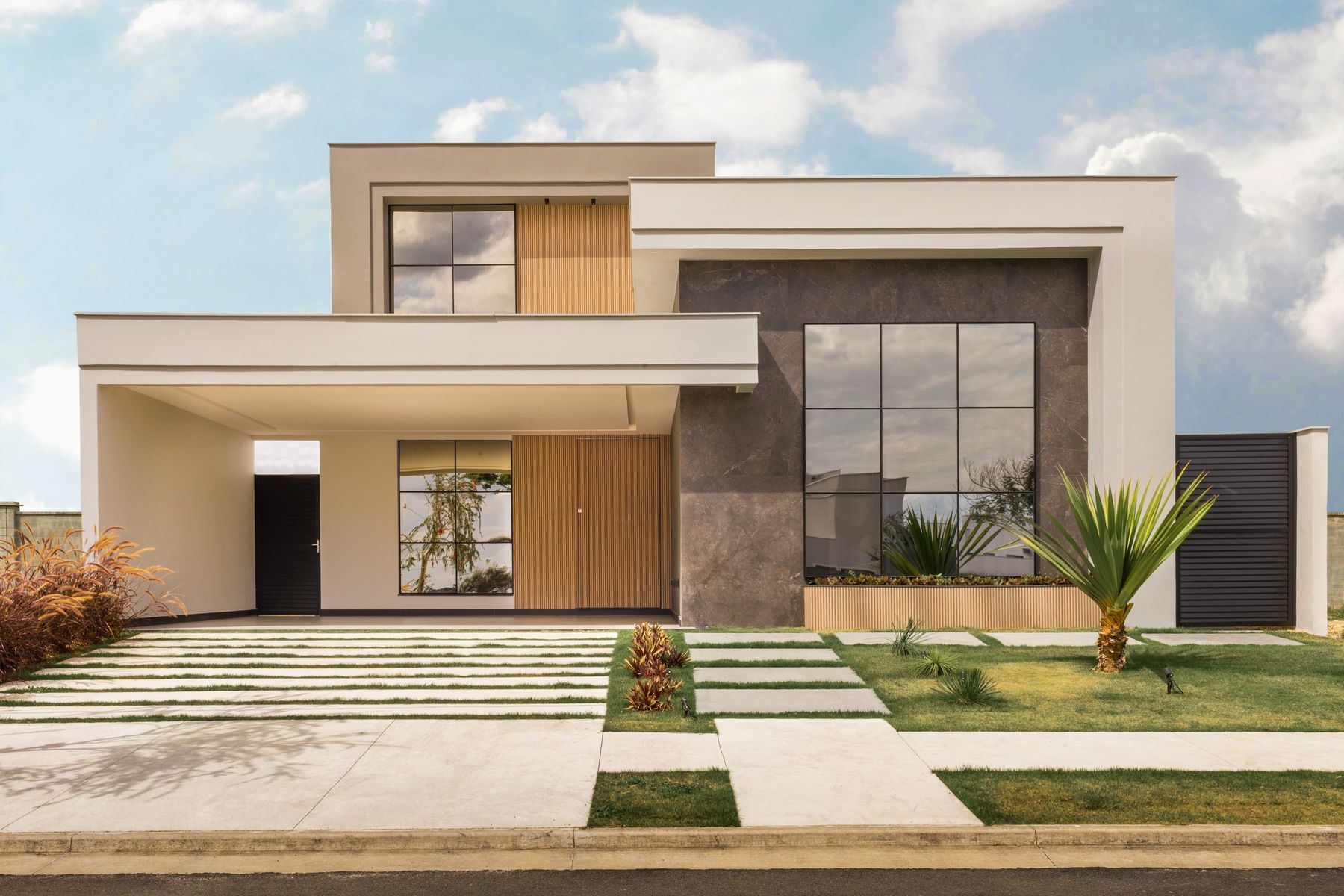 A contemporary home exterior with broad windows and a landscaped front yard.