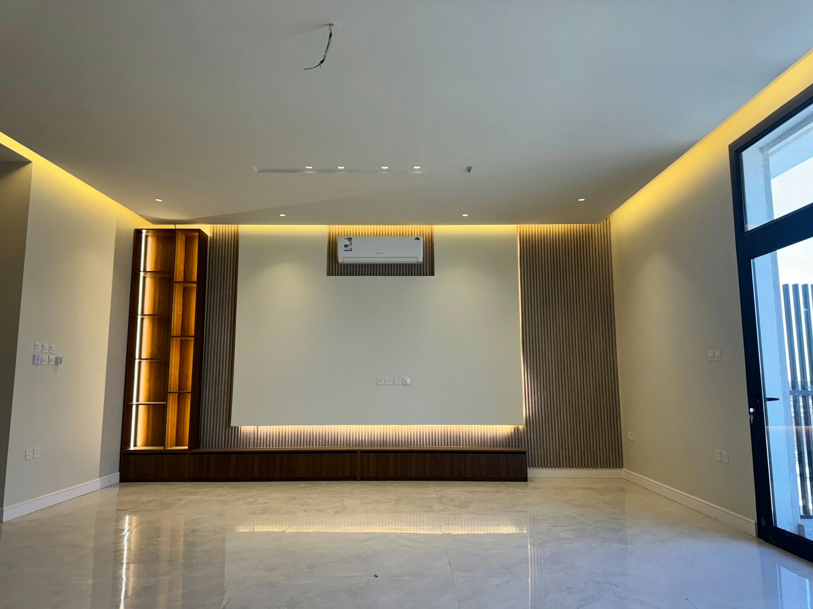 A wall-mounted air conditioner above a bright room with a large window.