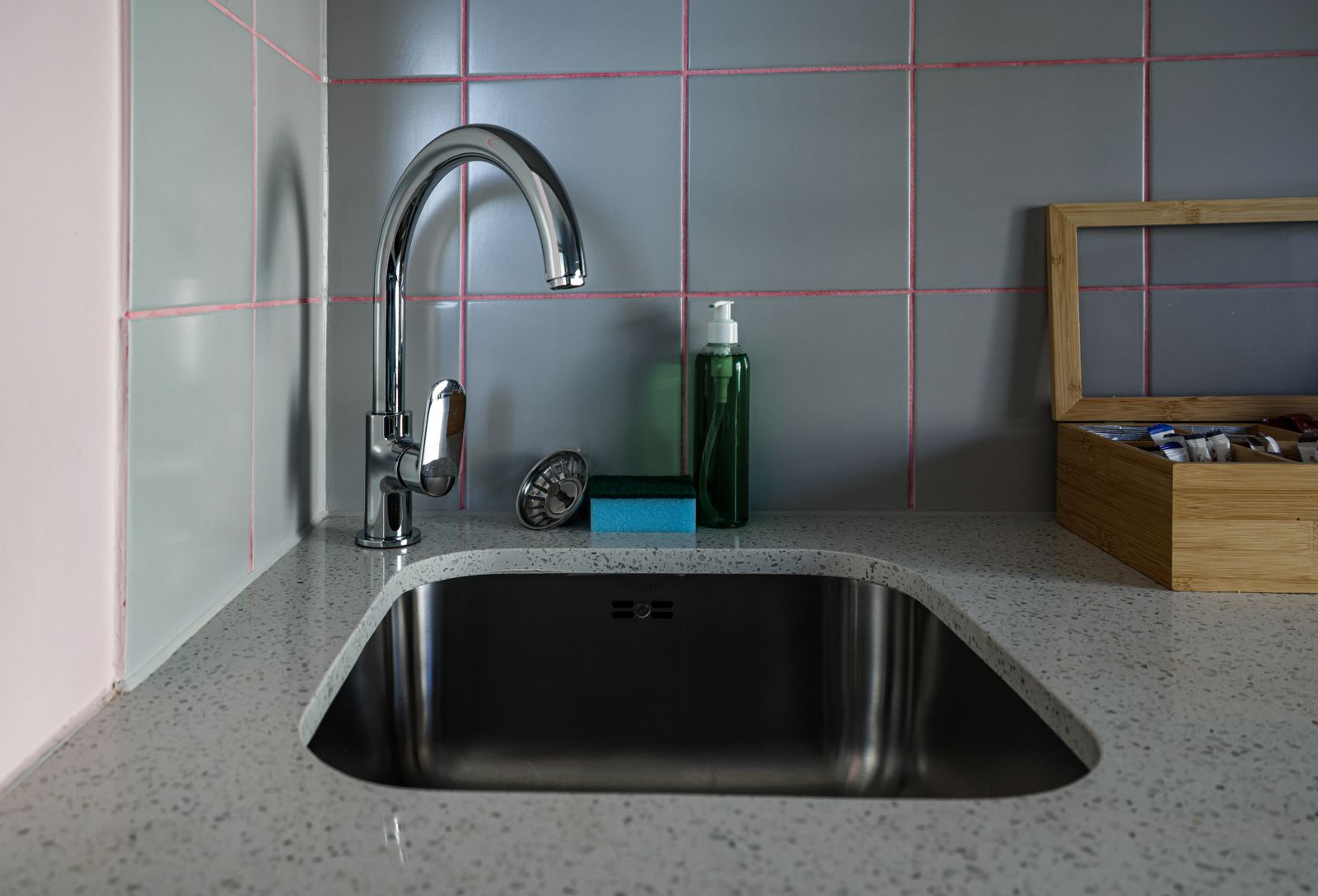 A chrome kitchen faucet and sink set into a light countertop.